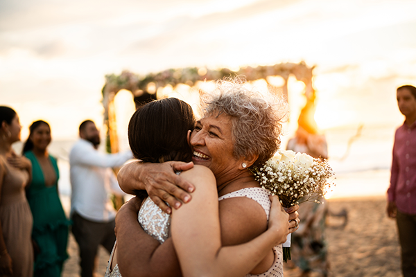 two women hugging at a wedding on the beach.